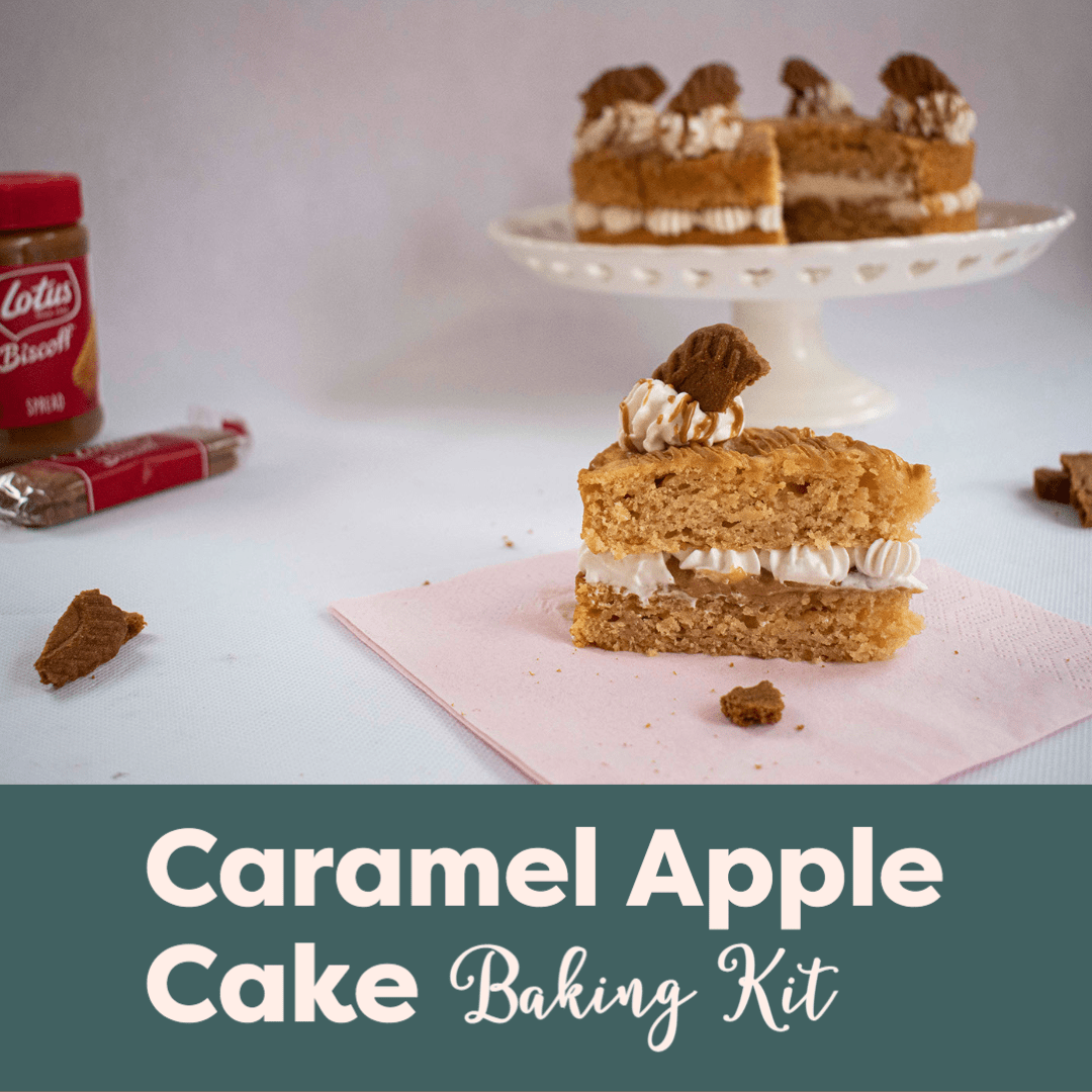 Caramel Apple Cake Baking Kit link, a slice of apple cake with Lotus Biscoff Spread and vegan cream filling, infront of the whole cake on a cake stand, decorated with vegan cream swirl and a biscoff biscuit. 